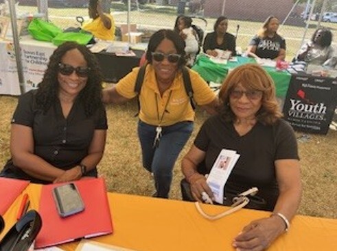 Three women sit and smile for a picture.