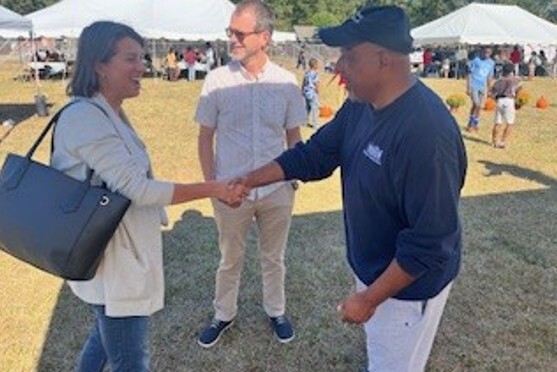 A woman and man smile and shake hands.