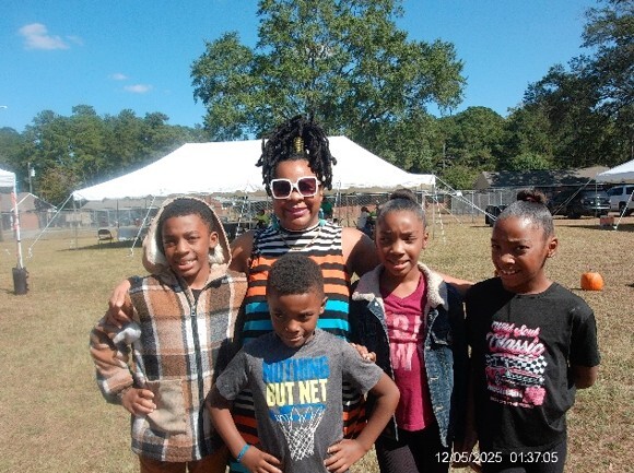 A woman smiles for a picture with four kids.
