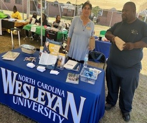 A man and woman stand at the North Carolina Wesleyan University table.