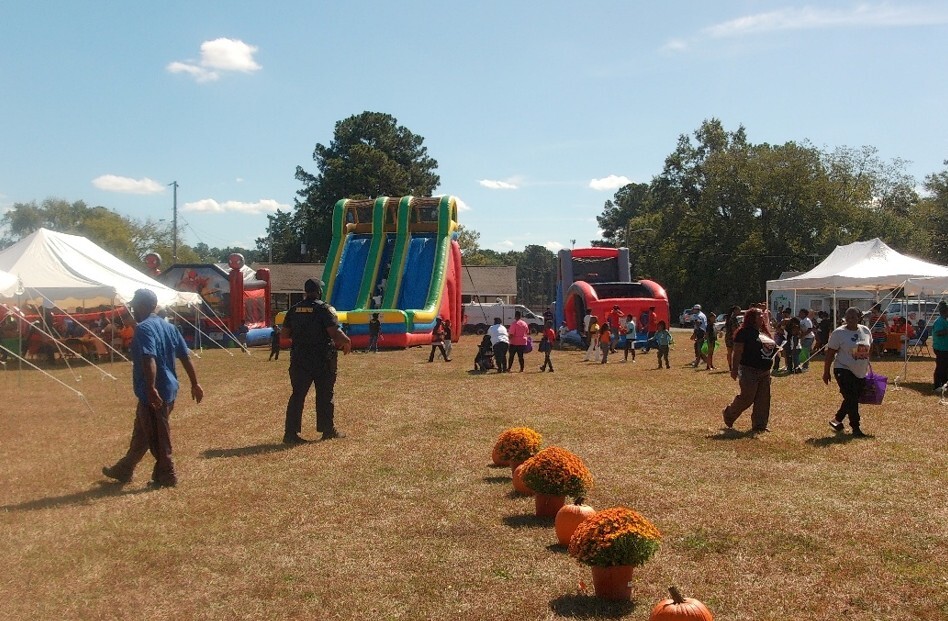 People walking around between tents and inflatable slides and bounce houses.