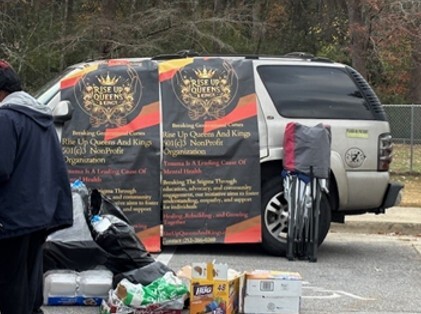 A suv with Rise up Queens and Kings banners on it.