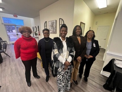 Five women stand and smile for a picture.