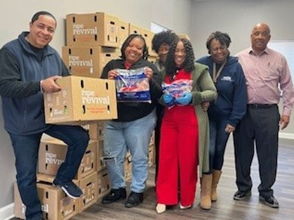 Six people stand with boxes of food, smiling for a picture.